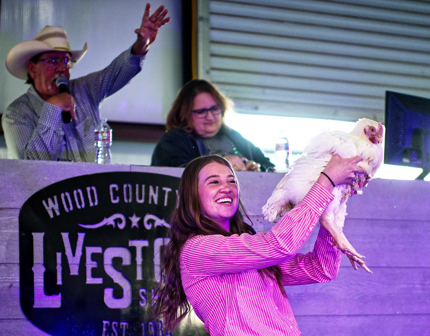 Ashlan Barnhart of Winnsboro enjoys showing her reserve champ broiler Friday as Kelly Conley auctions it off for $3,600. [see many more show moments]